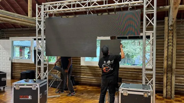 Técnicos armando una pantalla LED junto a los flight cases y el cableado de energía