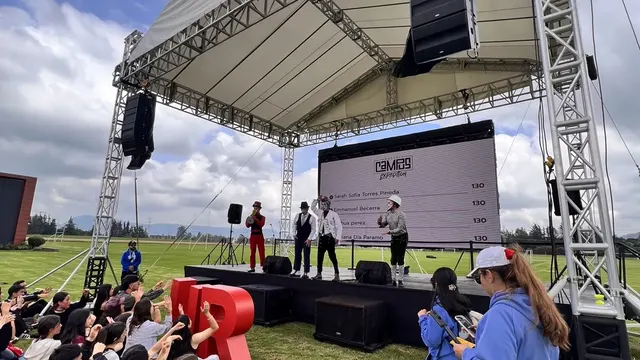 Pantalla LED outdoor bajo carpa en un evento al aire libre con público sentado en el césped