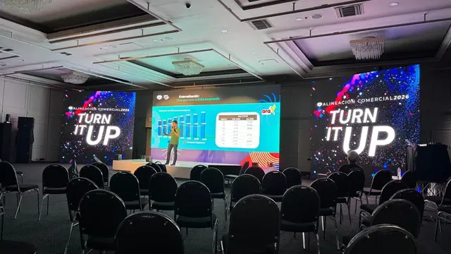 Pantalla LED panorámica con dos pantallas laterales en una convención, vista desde el fondo del salón
