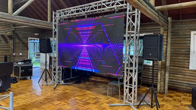 Pantalla LED sobre truss proyectando un visual de neón geométrico, con el detalle del píxel visible