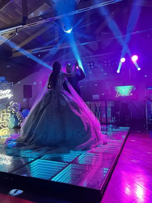 Vals de quince años con pista LED iluminada y pantallas mostrando el nombre de la festejada