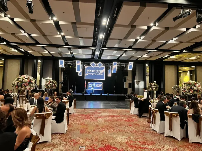 Salón decorado con arreglos florales y pantalla LED de fondo para una celebración de gala