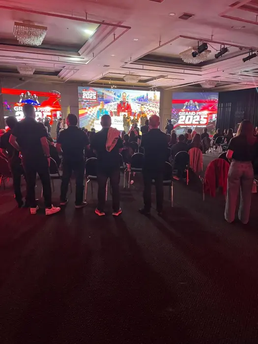 Público de pie frente a una pantalla LED en un evento corporativo con iluminación de color