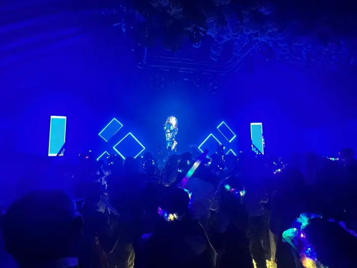 Fiesta con iluminación azul, humo y pantallas LED acompañando el show en tarima