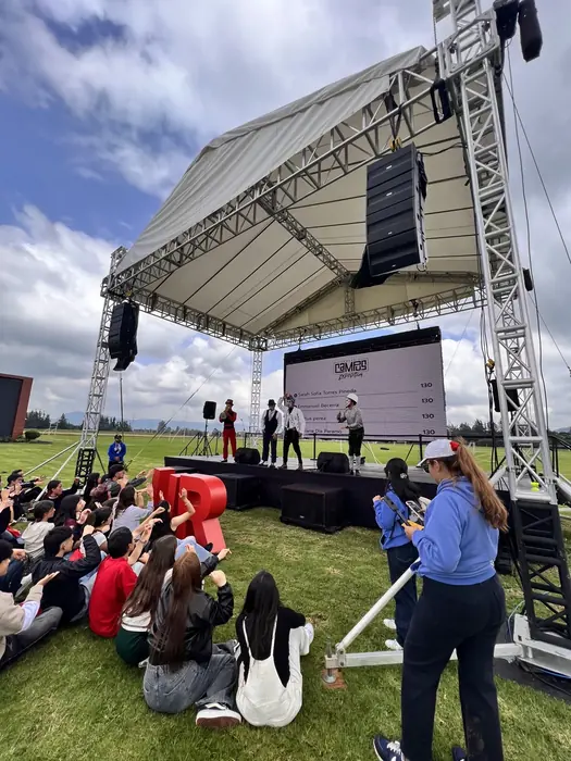 Pantalla LED outdoor bajo carpa en un evento al aire libre, con público sentado en el césped