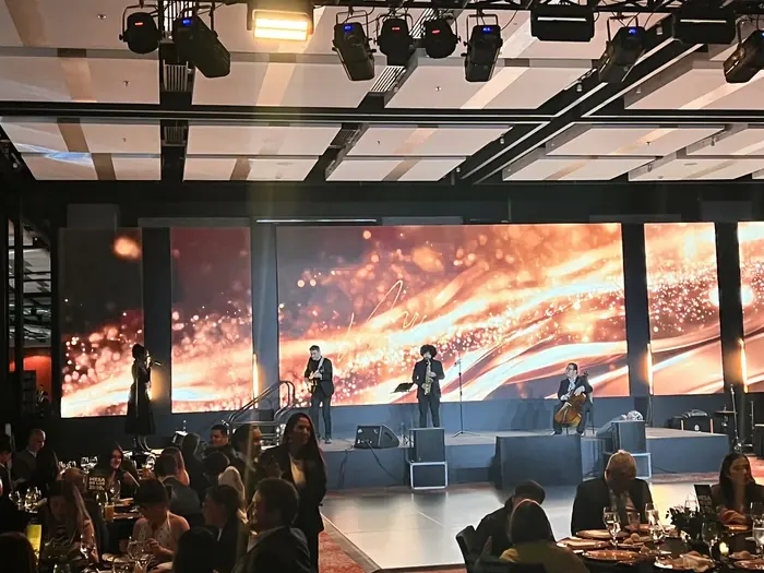 Pantalla LED panorámica con visual dorado detrás de una banda en vivo durante una gala