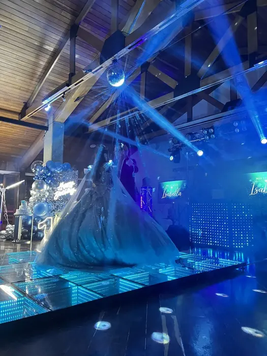 Quinceañera bailando el vals sobre una pista LED con pantallas laterales