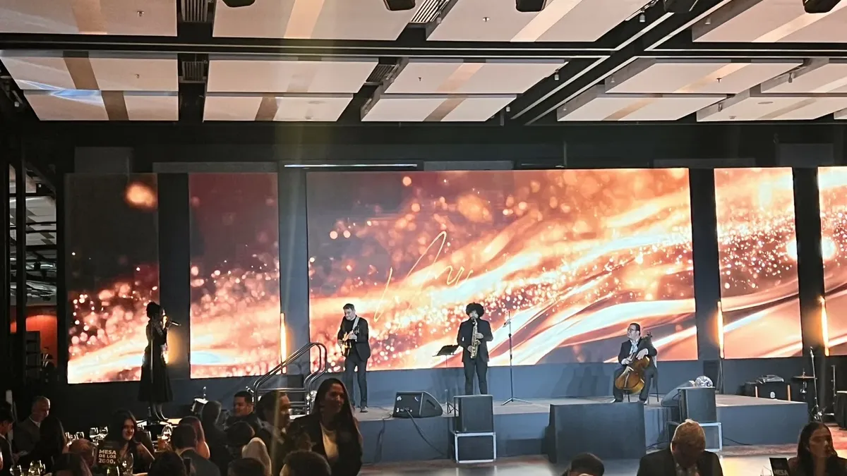 Pantalla LED panorámica con visual dorado detrás de una banda en vivo durante una gala en Bogotá